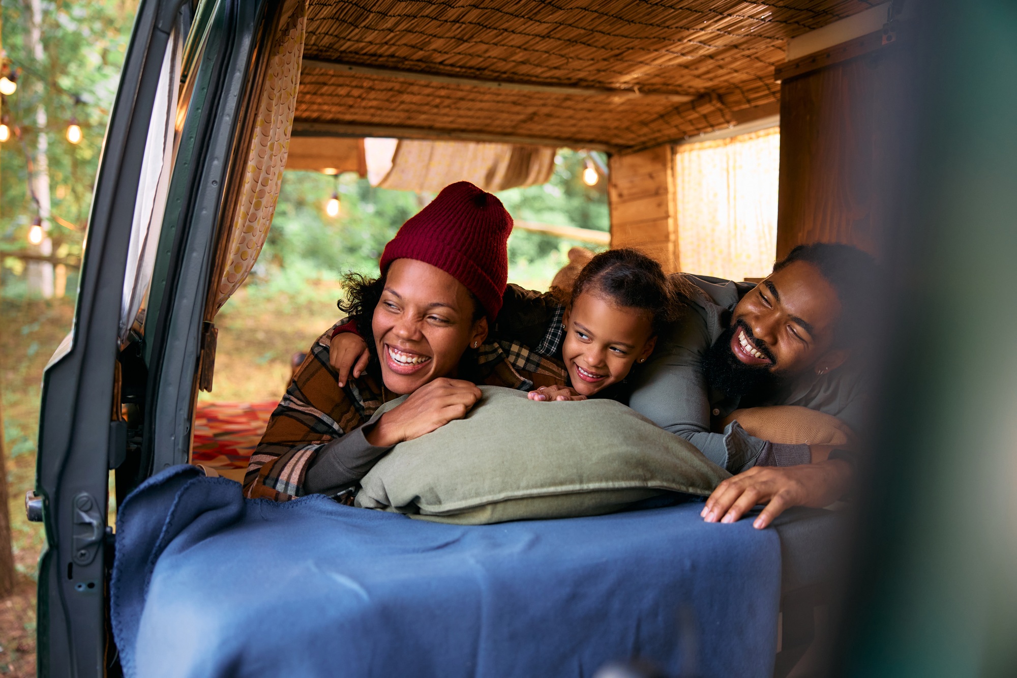 Cheerful black family relaxing in camping trailer in the woods.